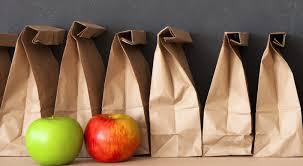 Row of brown paper bags with two apples, left one green and right was red, on the left side of image